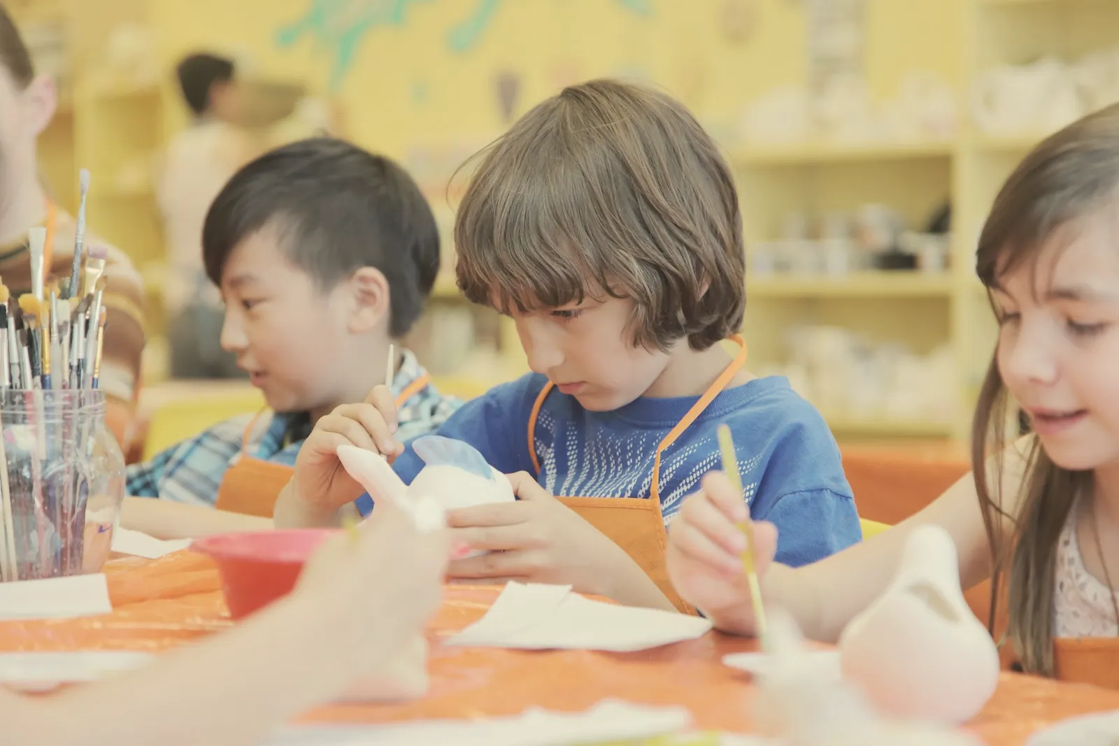 Kinder bemalen Keramik in einer Werkstatt